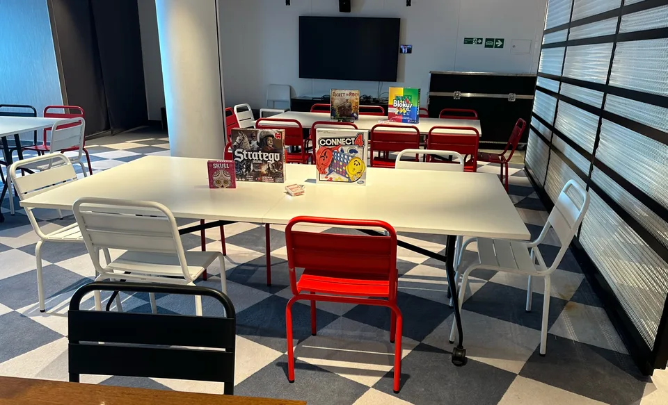 Onboard seating area with white tables and red and white chairs arranged around board games such as Connect 4 and Jenga.