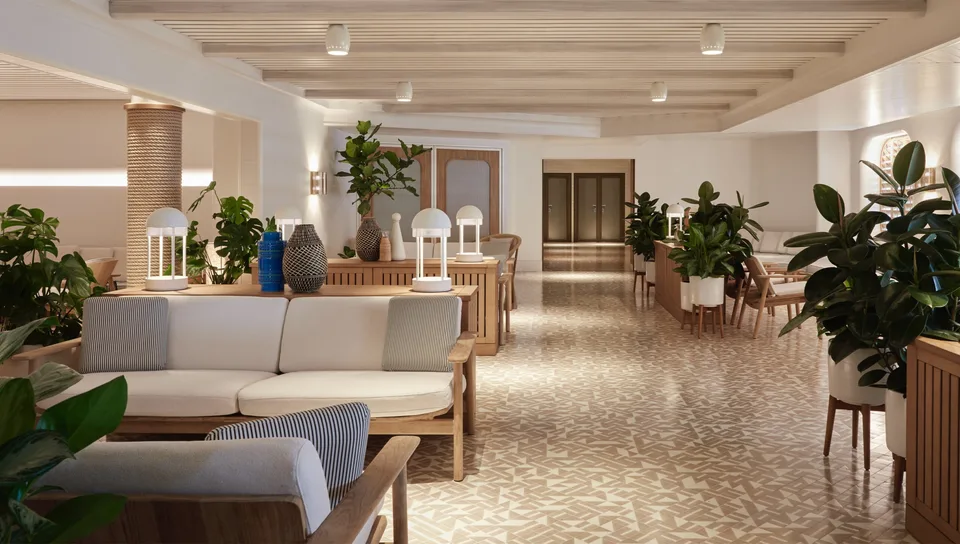 Interior view of a modern, spacious seating area with wooden furniture, indoor plants, and patterned tile flooring.